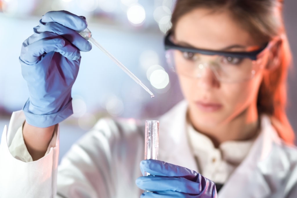 3130926490 Life scientists researching in laboratory. Focused female life science professional pipetting solution into the glass cuvette. Lens focus on pipette. Healthcare and biotechnology concept.